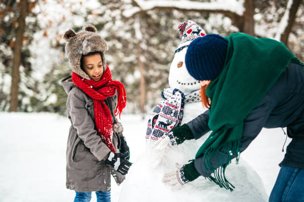 istock Mother and daughter making a snowman 1191969875