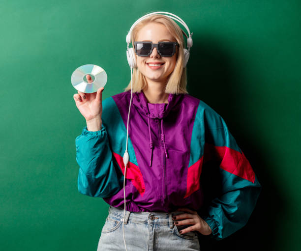 Style woman in 90s punk clothes with headphones and CD Style woman in 90s punk clothes with headphones and CD on aqua menthe color background compact disc stock pictures, royalty-free photos & images