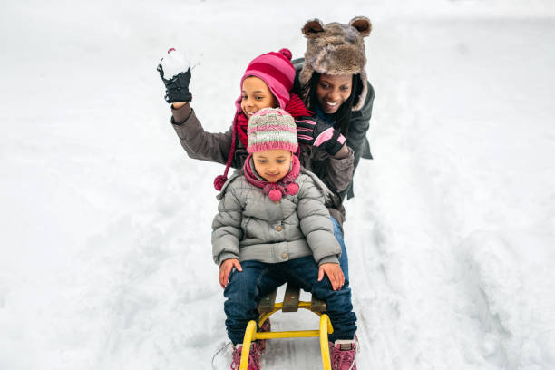 Kids enjoying winter fun, sliding downhill on colorful plastic sleds in a snowy park, creating joyful memories