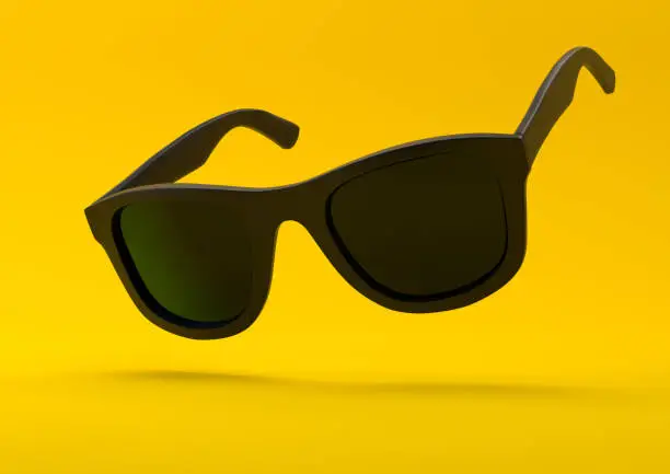 Photo of Black summer sunglasses falling down on a pastel bright yellow background
