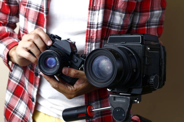istock Man holding a 35mm film camera and standing behind a medium format film camera on a tripod 1191978297