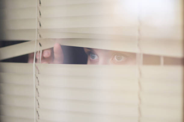 istock woman looking forward through the window blinds 1191982640