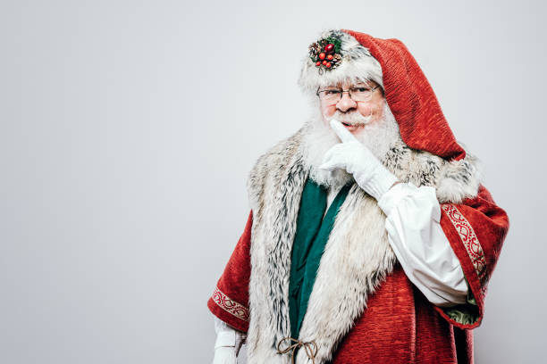Classic Santa Claus Christmas Portrait on White A portrait of a traditional Saint Nicholas or Father Christmas figure, wearing festive holiday clothing. Shot on white studio background. Horizontal with copy space. santa claus expressions shhh stock pictures, royalty-free photos & images