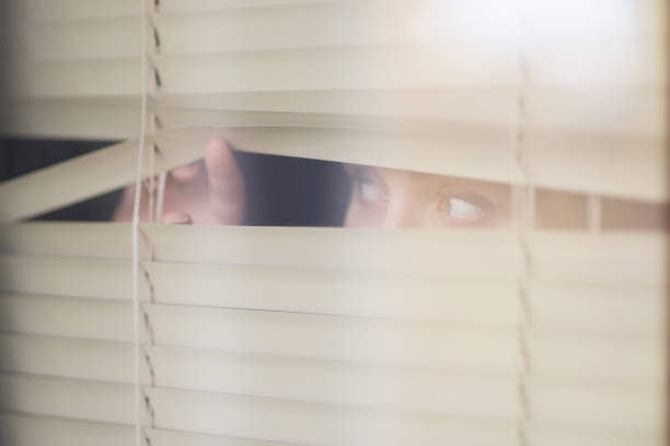 istock young woman looking through the blinds, waiting for something 1191987140