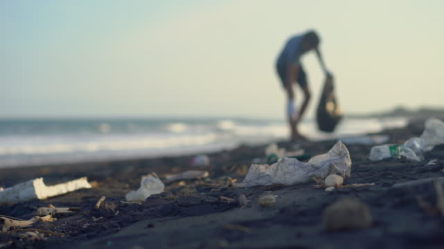 Young man clean up the beach from a trash