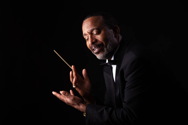 Mature man in tuxedo conducting with baton