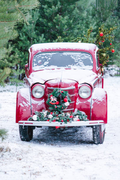 un'auto rossa con decorazioni natalizie e un albero di natale si trova in una foresta invernale. concetto di capodanno festivo. - christmas red snow humor foto e immagini stock