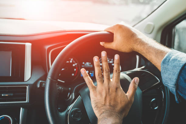 istock Hand man pushing car horn while driving car. 1192010429