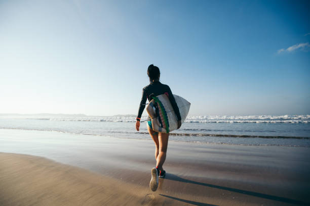 istock Woman surfer with surfboard on beach 1192012839