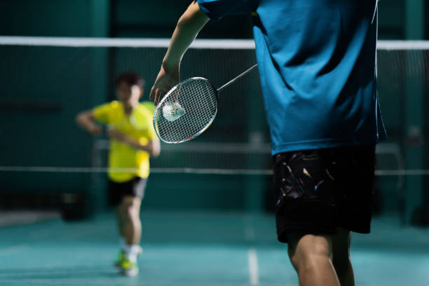 giocatore asiatico di badminton sta colpendo in tribunale - sport con racchetta foto e immagini stock