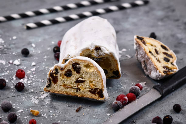 tranche d'aliments sucrés traditionnels allemands de la saison de noel appelés «stollen» ou «christstollen», un pain de fruits de noix, d'épices et de fruits secs ou confits, enrobés de sucre en poudre - christmas stollen christmas pastry baked photos et images de collection