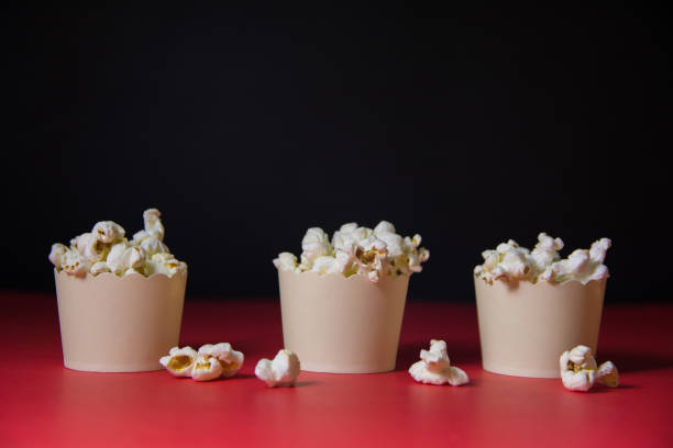 istock closeup of popcorn in small mini white popcorn three boxes on a red floor with a black background 1192027782