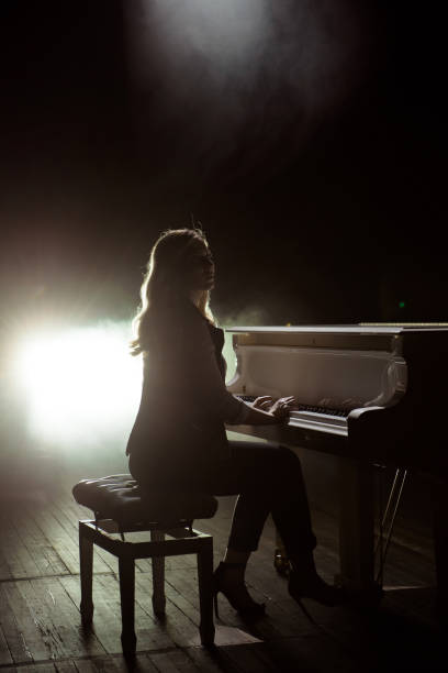 istock Female keyboards player on stage during concert, backlight 1192029835