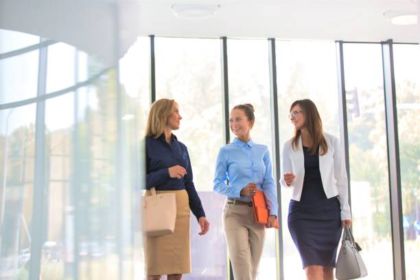 istock Smiling businesswomen talking while walking against window at office 1192035817
