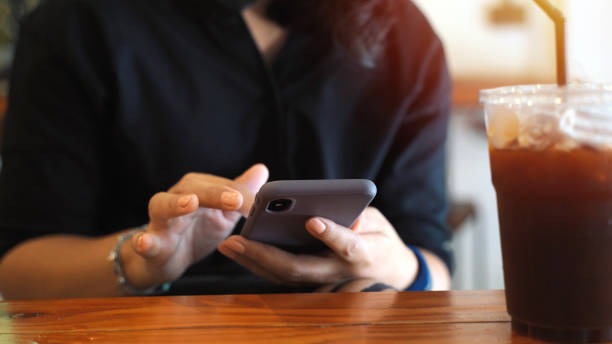 istock Young customer asian woman using smartphone while drinking iced coffee in the cafe, lifestyle and technology concept 1192038400