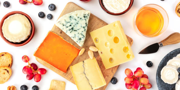 istock Cheese board, a flat lay panoramic shot on a white background. Blue cheese, red Leicester, Emmental, goat cheese, Brie and others with wine and fruits 1192038630