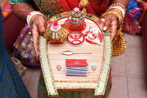 Bengali bride holding wedding accessories or Traditional Wedding Invitation card including sindoor box in Indian wedding