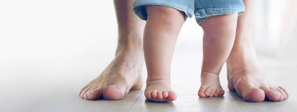 Taking her first tiny steps Cropped shot of an unrecognizable little baby girl learning to walk with her father behind her at home first steps stock pictures, royalty-free photos & images