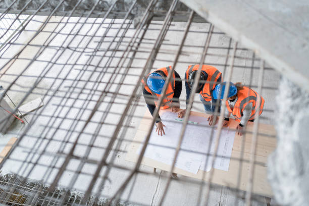 istock Foreman and forewoman discussing blueprint with architect 1192041836