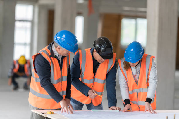 istock Foreman and forewoman discussing blueprint with architect 1192041842