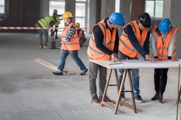 istock Foreman and forewoman discussing blueprint with architect 1192041844