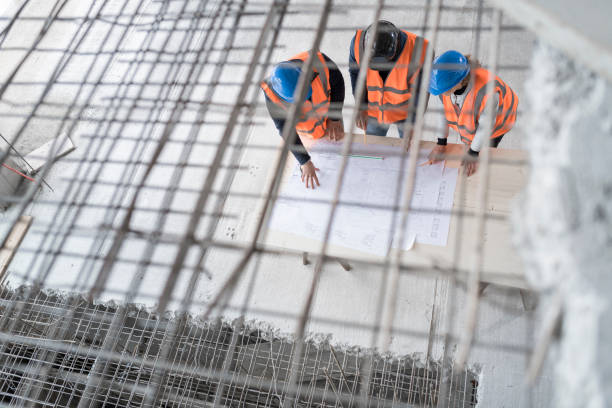 istock Foreman and forewoman discussing blueprint with architect 1192041850