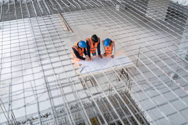 istock Foreman and forewoman discussing blueprint with architect 1192041851