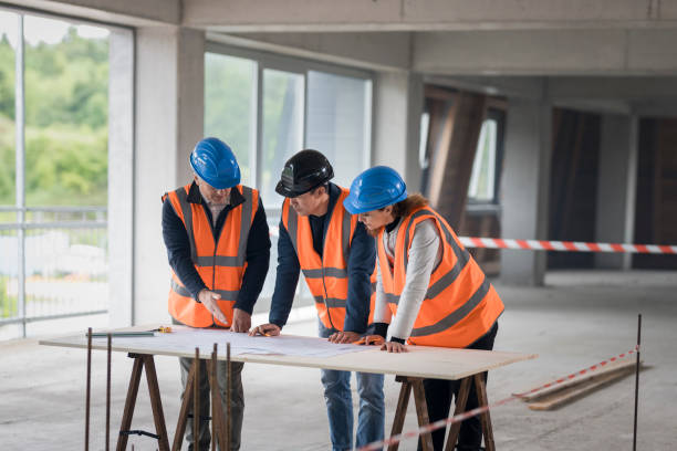 istock Foreman and forewoman discussing blueprint with architect 1192041865