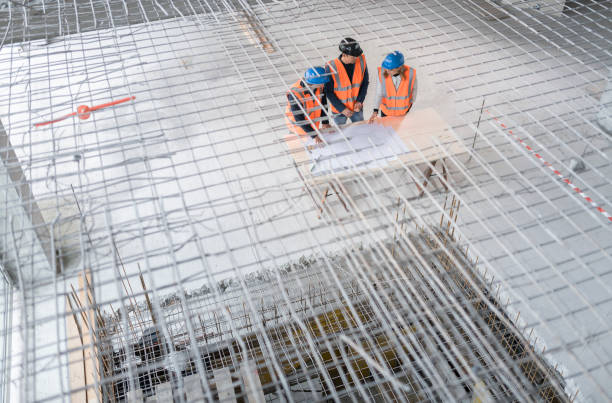 istock Foreman and forewoman discussing blueprint with architect 1192041869
