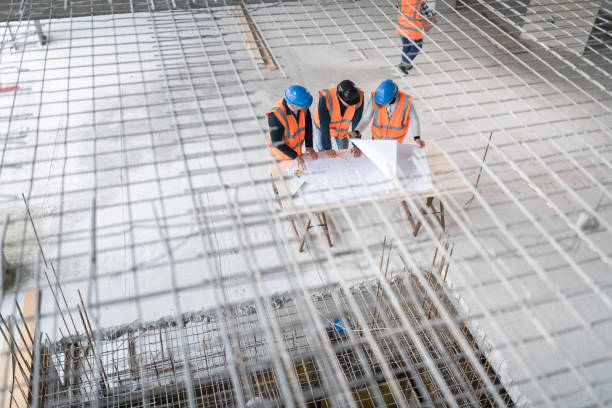 istock Foreman and forewoman discussing blueprint with architect 1192041870