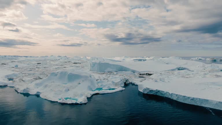 Slow and majestic drone aerial view over white ice bank, floe and icebergs in the area of Ilulissat, Greenland