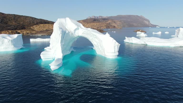 Slow and majestic drone aerial view over white and turquoise Icebergs floating in the calm Baffin Sea, Greenland,