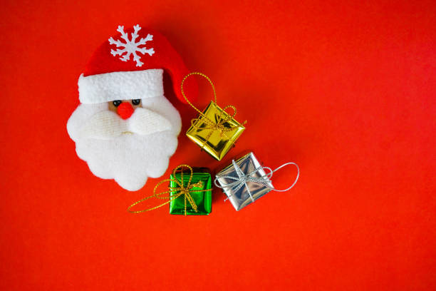 Santa Claus doll face with small gift boxes on grunge red paper , top view