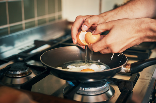 Cropped shot of an unrecognizable man frying eggs in his kitchen at home