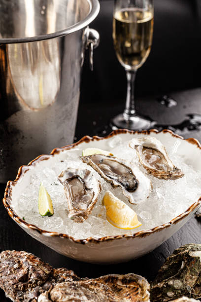 Prosecco bar concept. Open oysters lie on crushed ice with lemon and lime, next to a glass of champagne. Background image. Copy space.