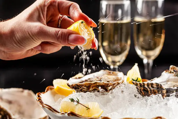Photo of Prosecco bar concept. Open oysters lie on crushed ice with lemon and lime, next to a glass of champagne. Background image. Copy space.