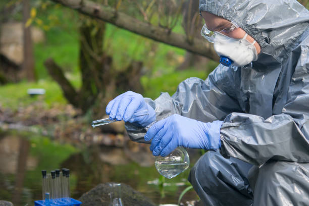 istock scientist, in a protective suit and mask, pours liquid from a test tube into a flask, for testing water 1192049621