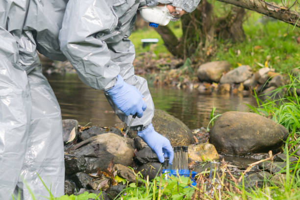 istock scientist, in a protective suit and mask, collects water from the river for testing, in test tubes 1192049640
