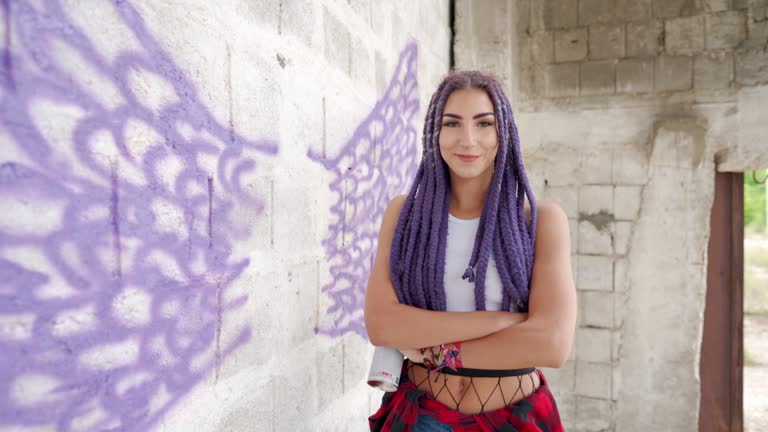 Young woman drawing graffiti on the brick wall