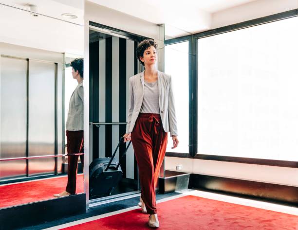 femme d'affaires sortant de l'ascenseur dans l'hôtel - departure hall photos et images de collection