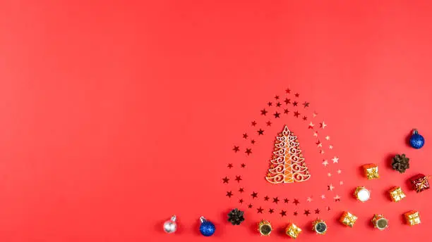 Photo of Concept of Christmas and New Year holiday and sale. Flat lay of wooden Christmas tree, confetti stars, cone and balls