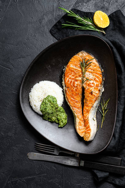 istock Grilled salmon steak garnished with rice and spinach. Black background. Top view 1192060568