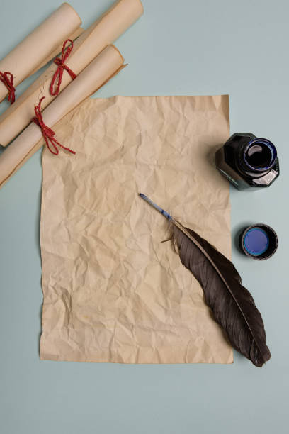 istock Raven feather, inkwell and old yellowed paper on red background. Copy space. 1192063487