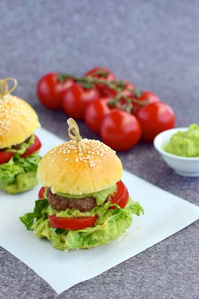 Sesame seed burger buns with beef patties, guacamole, tomato and lettuce