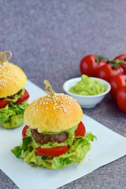 Sesame seed burger buns with beef patties, guacamole, tomato and lettuce