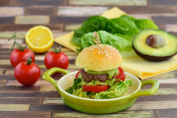 Sesame seed burger buns with beef patties, guacamole, tomato and lettuce