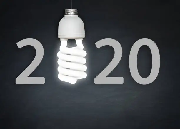 Photo of New Year 2020 concept light bulb and blackboard.