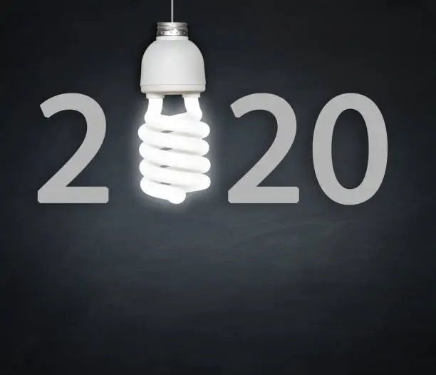 Photo of New Year 2020 concept light bulb and blackboard.