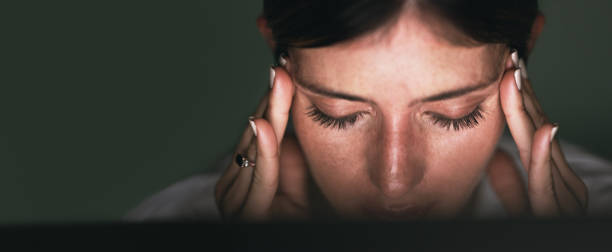 This headache is starting to worsen Closeup shot of a young businesswoman looking stressed out while working in an office at night headache photos stock pictures, royalty-free photos & images