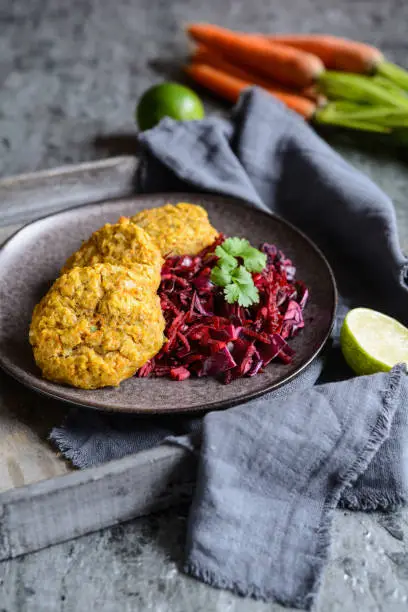 Healthy fritters made from red lentils, carrot and rolled oats served with red onion and cabbage